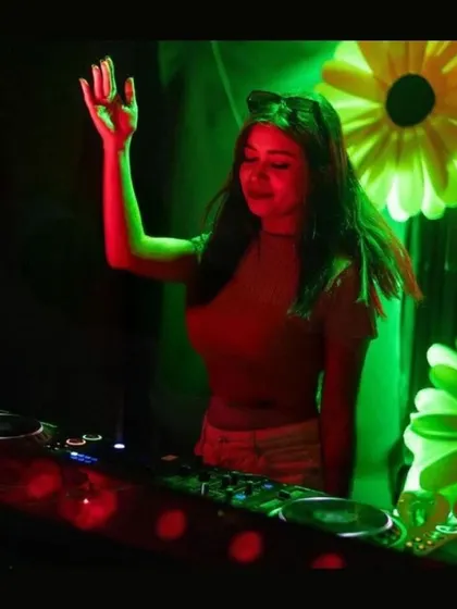 Raising a hand to connect with the crowd at Cosmic House, Vizag. The green and red lights against the floral background were just beautiful.