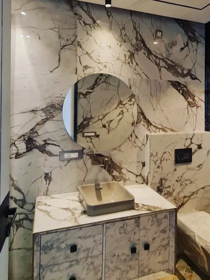This bathroom design uses a stunning white and brown veined marble for the walls and vanity, creating a bold and creative space.