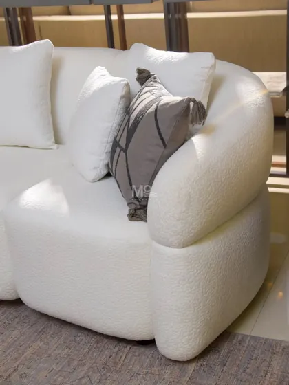 A closer look at the Aether Sofa's distinctive curved arm. The high-quality bouclé fabric adds visual depth and a touch of cozy sophistication, making it a perfect piece for modern, serene interiors.