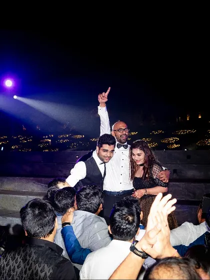 A triumphant moment on the stage as the groom is celebrated by his friends and family during the reception party.