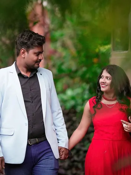 A candid walking shot of a couple through a lush, green path, framed by leaves.