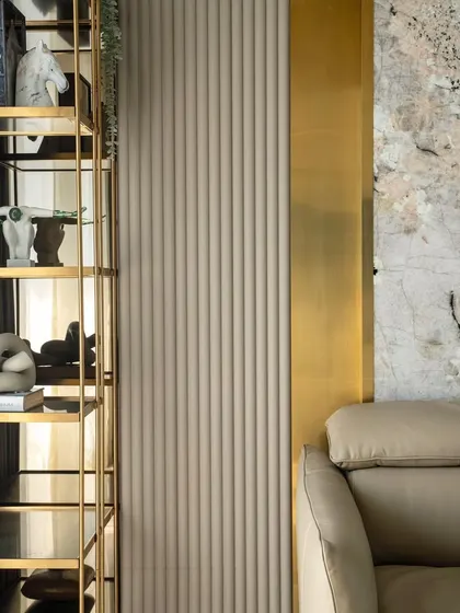 A detail shot of the den bedroom in the 'Urban Oasis' project. The image highlights the mix of textures, including fluted wall panels, brass accents, and abstract art pieces on the shelf.