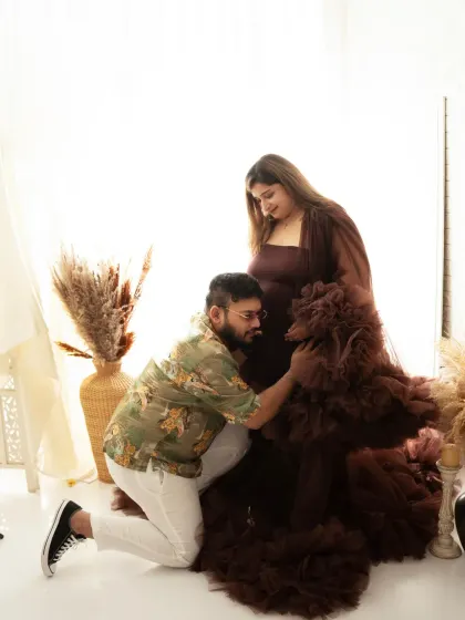 A tender moment captured. The father-to-be kneels to connect with the baby bump, a simple and heartfelt pose during their maternity session.