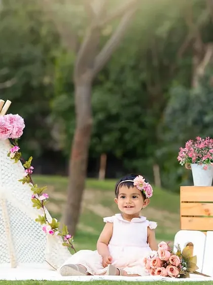 A beautiful outdoor portrait session featuring a pink floral theme with a teepee, perfect for a sunny day in the park.
