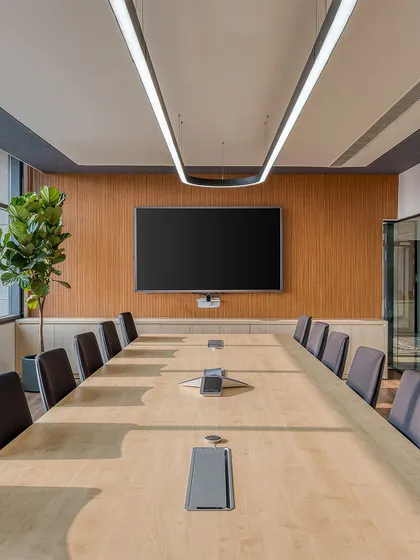 The main conference room at Laurus Labs. A wood-paneled feature wall and minimalist lighting create a professional and focused environment, with large windows providing ample natural light.