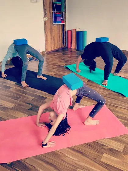 Kids using blocks in Chakrasana, or Wheel Pose, to help with alignment and lift. This shows how props can make advanced poses more accessible and fun.