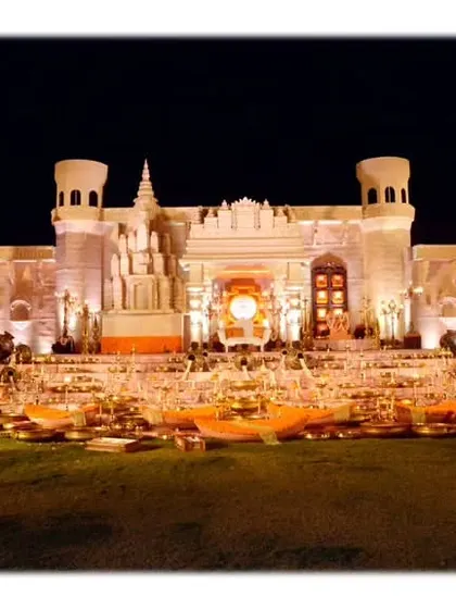 A grand stage designed to replicate a Banaras Ghat, complete with temple architecture and steps adorned with traditional brass lamps and offerings.