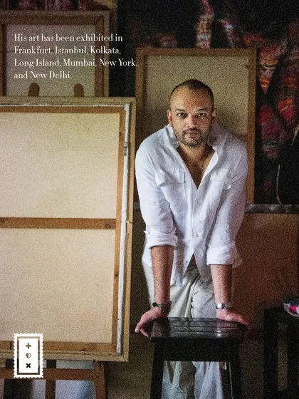 A powerful portrait of artist Pushkar Thakur in his studio, leaning against a stool. The image includes text about his international exhibitions.