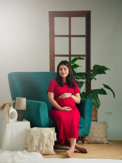 A pop of color with a vibrant red dress and a teal armchair. This studio setup is perfect for clients who want a bright and cheerful maternity session.