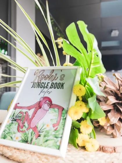 A framed sign for "Roohi's Jungle Book Vibes" featuring King Louie, nestled among tropical leaves and flowers, adds a fun, character-driven detail to the decor.