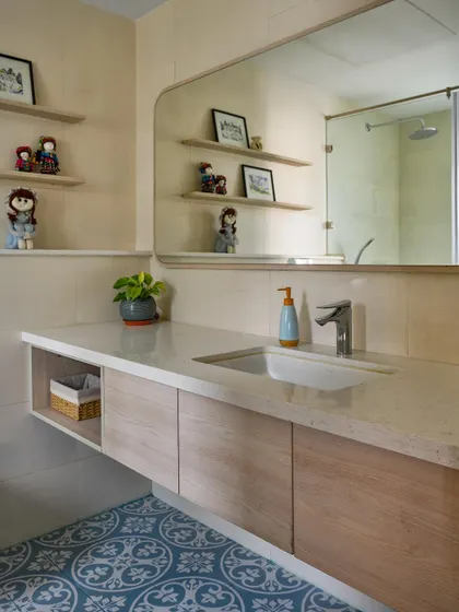 This bathroom features a floating vanity, a large custom mirror, and open shelves for displaying personal items, all set against bold blue patterned floor tiles.