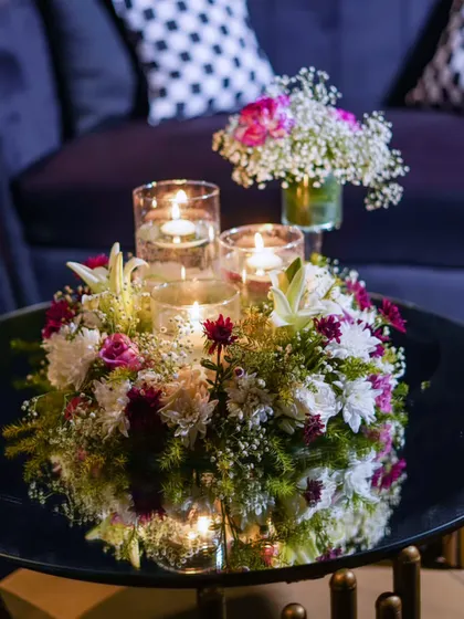 A close-up of a floral centerpiece with floating candles. This small detail adds warmth and elegance to a side table in the lounge area.