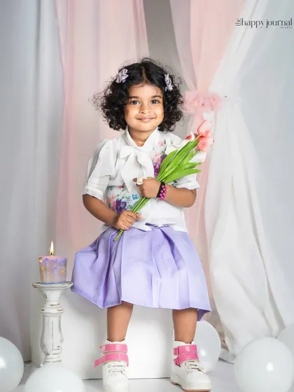 A curly-haired girl holding a bouquet of tulips. The soft lighting and pastel colors create a dreamy and beautiful studio portrait.