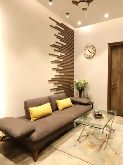 A closer look at the lounge's feature wall, where polished wooden battens create a dynamic, modern pattern behind the comfortable brown sofa.