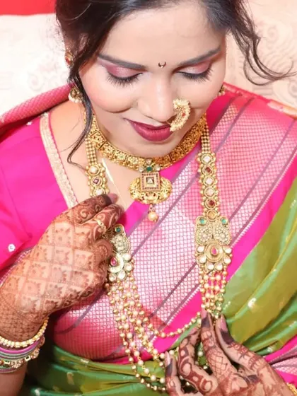 A bride admiring her beautiful layered Maharashtrian necklaces. The combination of a short choker and a long, elaborate haar creates a rich and authentic look.