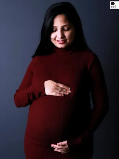 A gentle smile from the mother-to-be as she cradles her bump in this classic, elegant studio maternity portrait.