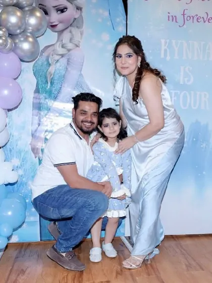 A happy family photo in front of the Frozen-themed backdrop at their daughter's 4th birthday party.
