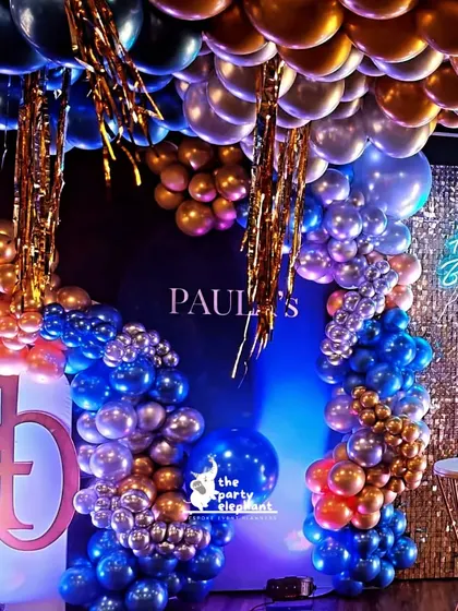 This shot showcases the rich textures and colors of the blue and gold party, with metallic balloons, a sequin backdrop, and a neon sign all coming together to create a visually stunning effect.
