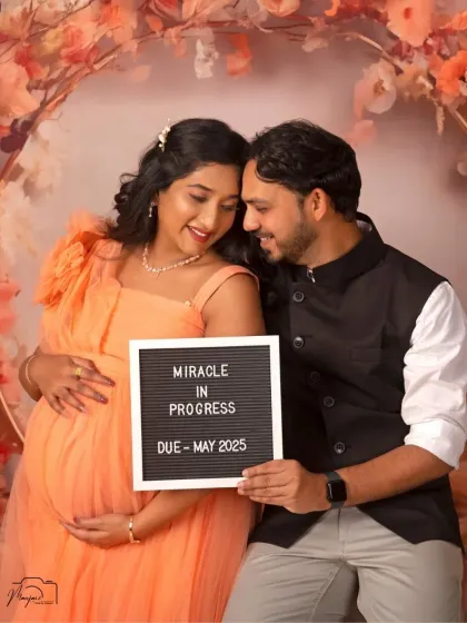 "Miracle in Progress." This couple shares their joy with a cute announcement board, creating a personal and memorable portrait.
