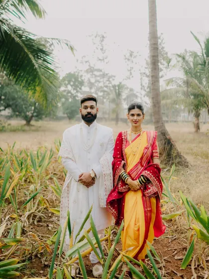 A formal yet beautiful portrait of the couple standing together amidst nature. This image showcases the grandeur of their traditional outfits and their strong presence as a couple.