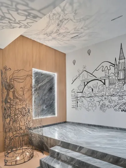 This monochrome mural is a surrealist travelogue, a memory reel of a family's adventures. The line illustration seamlessly transitions from the wall into a 3D metal sculpture, blending two-dimensional drawing with three-dimensional form to tell a continuous story.