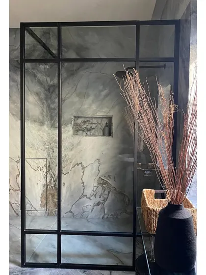 A bathroom in Bungalow No. 4, a renovation project in Nashik. This work-in-progress shot shows the installation of dramatic grey marble and a modern, black-framed shower enclosure.