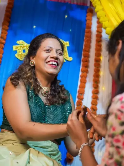 A moment of shared laughter between the bride and a friend during the mehendi application.