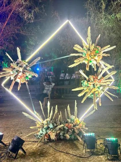 A modern and abstract photo booth for the Sangeet, using a neon diamond frame and explosive floral arrangements.