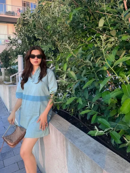Posing against a green backdrop to make the light-wash Calvin Klein denim dress pop.