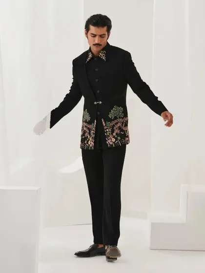 A full-length view of the black floral embroidered bandhgala from the Nazaakat collection. The asymmetrical design and unique clasp make it a modern classic.