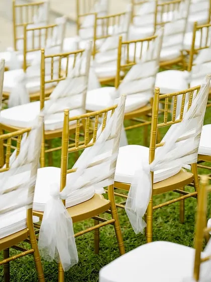 A close-up of the gold chairs adorned with delicate white sashes. This simple yet elegant detail elevates the look of the entire seating arrangement.