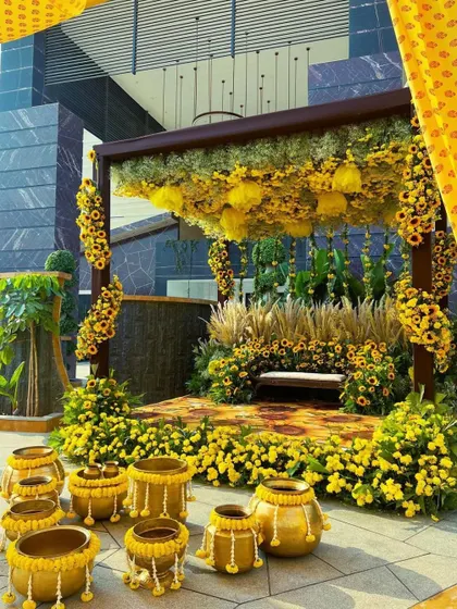A wider angle of the sunflower Haldi setup, showing how it transforms an outdoor space next to a modern building into a traditional, festive area.