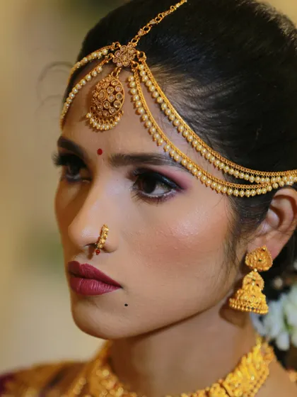 A pensive and beautiful profile shot of a bride, highlighting her traditional matha patti and jhumka earrings.