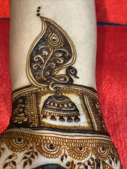 A still shot of the unique peacock and jhumka design. The combination of the bird and the earring motif creates a beautiful and symbolic piece of art on the arm.