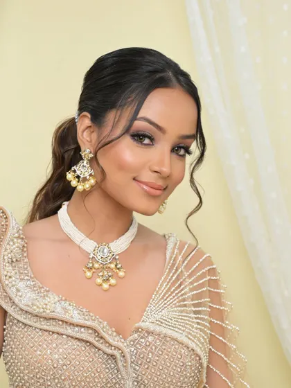 A smiling portrait that captures the fresh and modern feel of this look. The messy ponytail and glowing skin create a vibe that is effortlessly chic.
