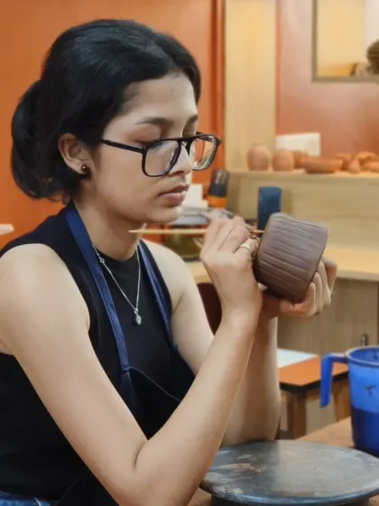A student meticulously carves fine lines into her hand-built mug. This demonstrates how simple texturing can add a professional and artistic touch to a piece.