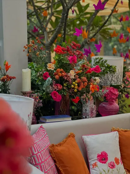A detail shot showing the mix of textures and colors, with embroidered cushions, bright flowers, and hanging paper cranes.
