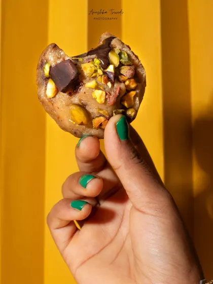 A close-up shot of a half-eaten pistachio and chocolate chunk cookie, showing off its delicious interior.