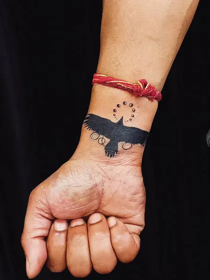 After: We used a solid black crow silhouette to completely cover the old name. The design is simple, bold, and effective, providing a clean and striking wrist tattoo.
