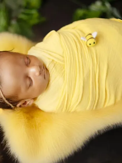 A close-up of our little honeybee, wrapped snugly in a yellow swaddle. The tiny bee detail adds a cute touch to this themed newborn portrait.