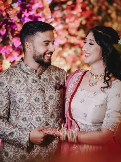 A close-up of the couple sharing a happy, intimate moment against a vibrant floral backdrop. The bright colors make their smiles pop.