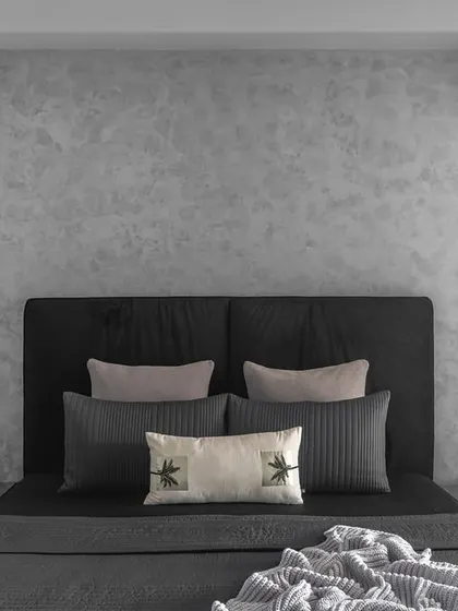 The daughter's bedroom uses a sophisticated palette of grey and black. Textured grey walls behind the bed add depth, while the simple black headboard creates an elegant and serene haven.