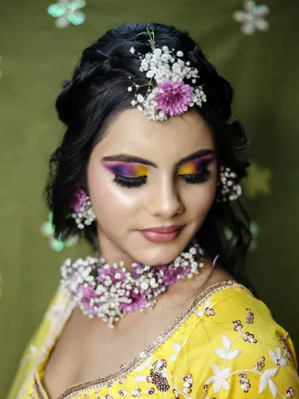 A vibrant Haldi ceremony look with floral jewelry and colorful eye makeup. We teach students to create specialized looks for every pre-wedding event.