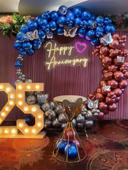 A 25th-anniversary celebration with a balloon ring in blue, silver, and rose gold. I used large '25' marquee numbers and butterfly accents.