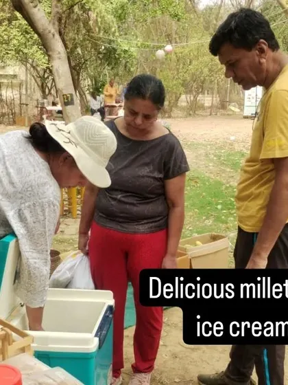 A customer trying a sample of delicious millet ice cream from a vendor's cooler.