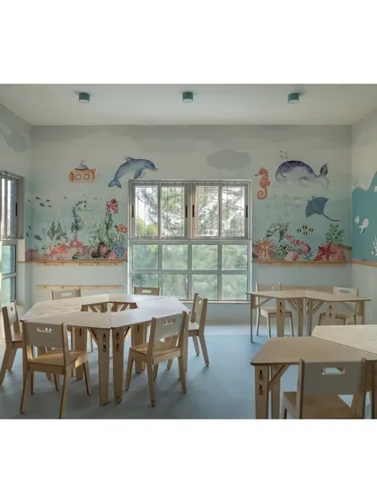 An overview of the aqua-themed classroom, showing how the light blue tones and underwater murals create a cohesive and calming world. The modular wooden furniture is perfectly scaled for young learners.