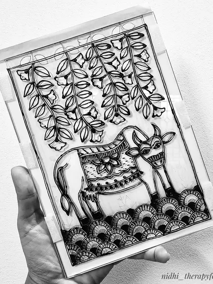 The black and white outline for a Madhubani-style cow painting on a sheet of glass. This is the first step before applying the vibrant glass colors.