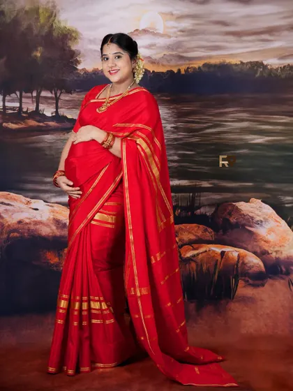 A full-length portrait showcasing a beautiful red saree against our painted landscape backdrop. This classic pose highlights the elegance of both the attire and the mother-to-be.