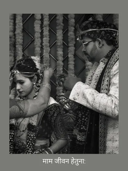 A black and white shot capturing the solemn moment the groom ties the sacred thread, with the Sanskrit phrase "Mam Jeevan Hetuna" signifying "you are the purpose of my life."