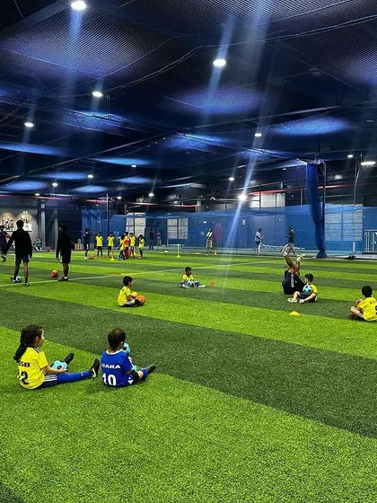 Kids taking a break on the turf. Rest and recovery are just as important as the drills themselves, and we ensure sessions are well-paced for young children.